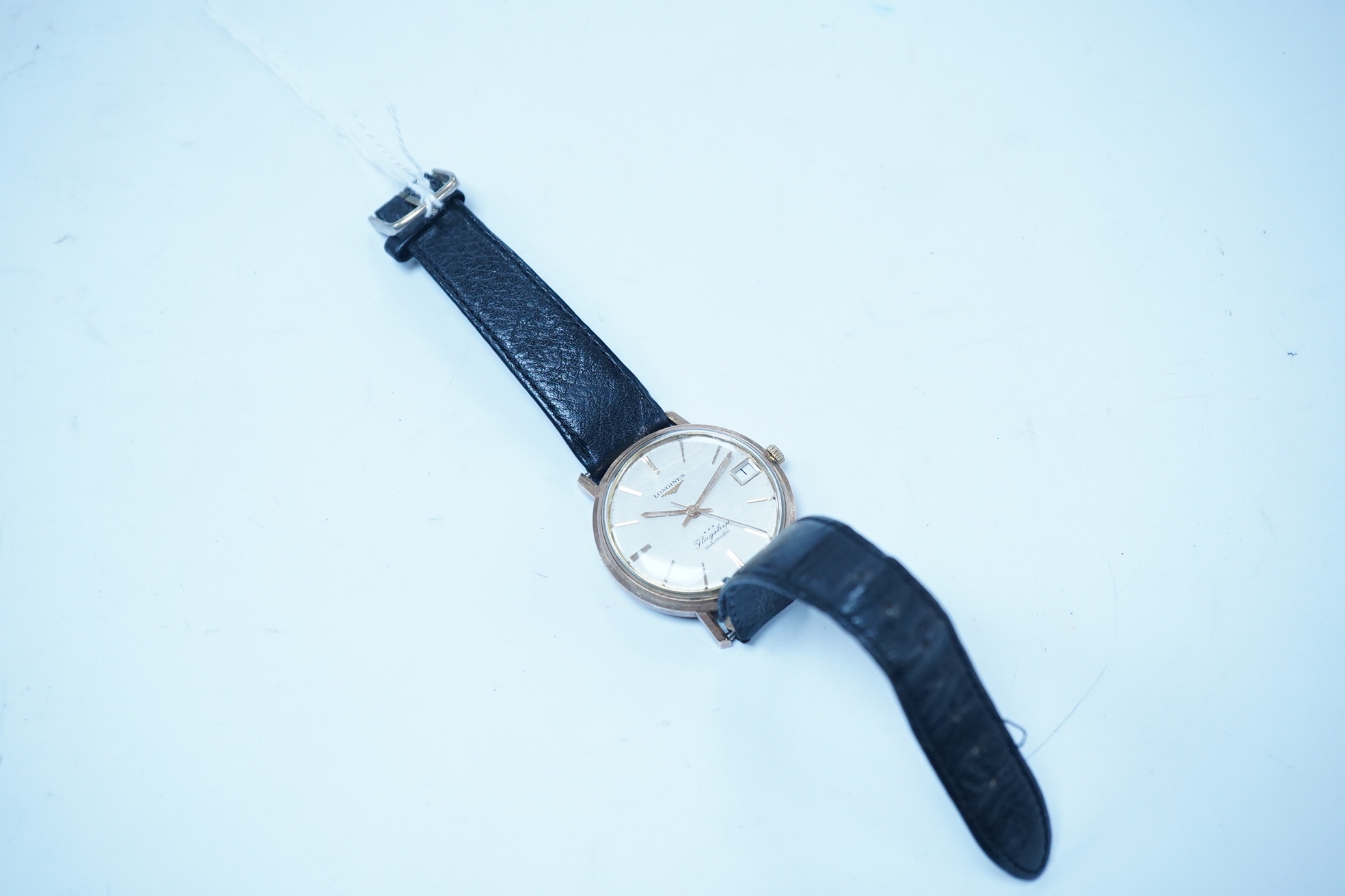 A gentleman's 9ct gold Longines Flagship automatic wrist watch, with baton numerals and date aperture, case diameter 35mm, on an associated leather strap. Condition - poor to fair